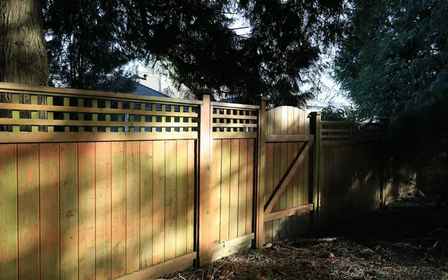 Stained wood privacy fence with a lattice top and a matching gate