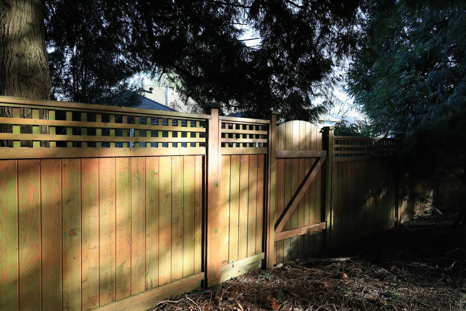 Stained wood privacy fence with a lattice top and a matching gate