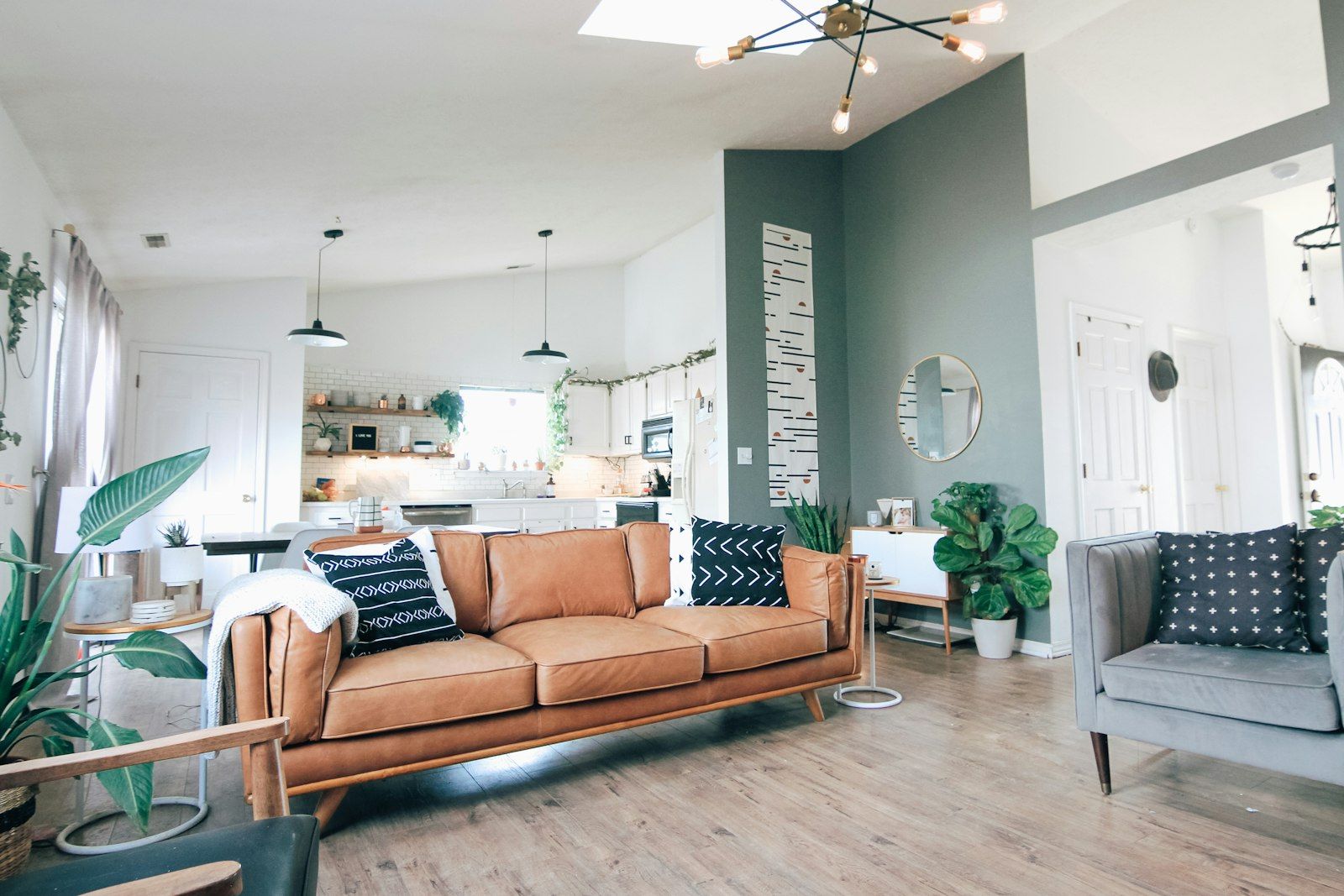 Bright living room with a muted teal accent wall and a tan leather sofa