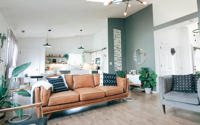 Bright living room with a muted teal accent wall and a tan leather sofa